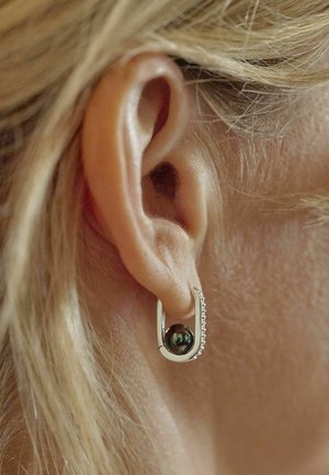 Orecchino a cerchio in argento con una perla scura al centro, decorato con piccoli cristalli trasparenti su un lato.