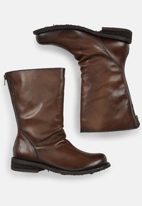 Bottes en cuir marron à la cheville avec un design ample, fermeture éclair sur le côté et un petit talon empilé. Texture lisse avec un branding subtil sur le talon.