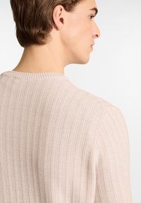 Hellrosa, gerippter Strickpullover mit rundem Ausschnitt und strukturiertem Stoff. Die Seitennähte sind sichtbar, mit einer taillierten Silhouette.
