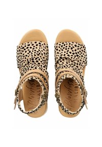 Béžové sandály s černými skvrnami, měkký textilní svršek, široké pásky, nastavitelné spony kolem kotníku a strukturovaná podrážka pro lepší grip.