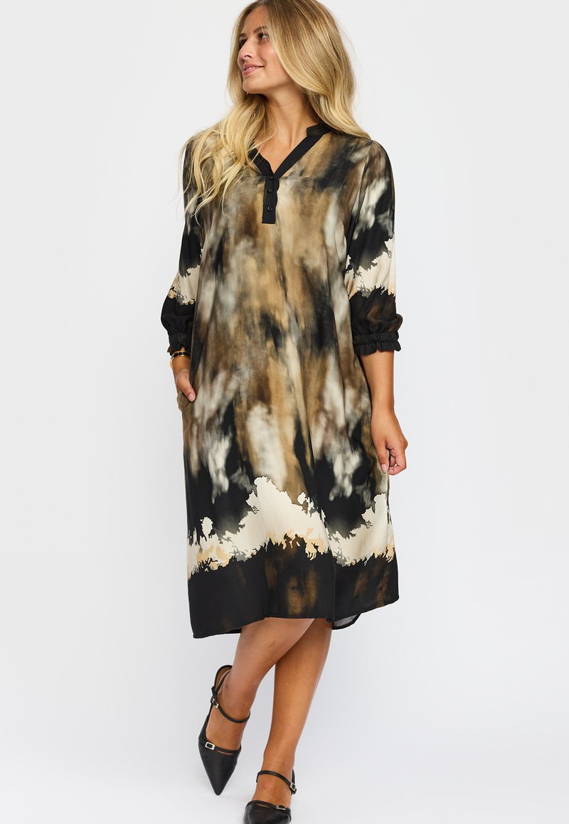 Långärmad klänning med ett svart, beige och brunt tie-dye mönster, med knappad V-ringning och elastiska manschetter. Inkluderar sidofickor.