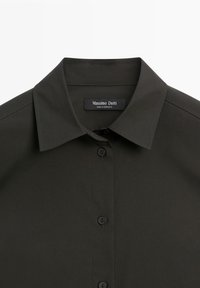 Dark green collared shirt with black buttons, featuring a smooth texture and a tag labeled "Massimo Dutti, made in Morocco" inside the collar.