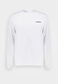 Valkoinen pitkähihaine t-paita, joka on valmistettu puuvillasta. Esittelee pienen mustan "patagonia"-logon vasemmassa rinnassa. Yksinkertainen, suora leikkaus.