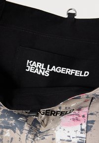 Μαύρο εσωτερικό ύφασμα με ένα ταμπελάκι που φέρει τη φράση «KARL LAGERFELD JEANS» με έντονα λευκά γράμματα. Το εξωτερικό υλικό παρουσιάζει ένα πολύχρωμο αφηρημένο σχέδιο.