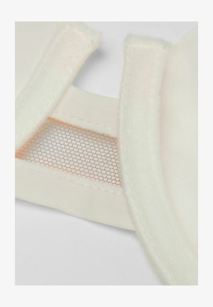 Weicher beiger Stoff mit einem Mesh-Detail und einer plüschigen Kantenverzierung, der eine strukturierte Oberfläche und sichtbare Nähte für Struktur und Halt bietet.