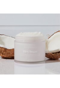 Frosted glasskrukke merket "Hey Sugar," som inneholder hvit kroppsskrubb, ved siden av en halv kokosnøttskall, glatt tekstur og minimalistisk design.