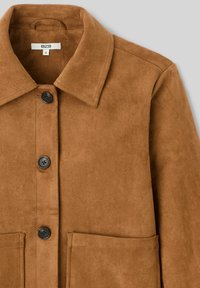 Veste en suède marron avec un col évasé, trois boutons noirs et deux poches avant. Texture douce et design ajusté.