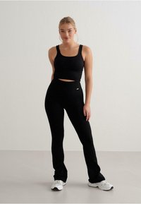 Svart ribbat kort topp och högmidjade leggings, båda med en åtsittande passform. Leggingsen har ett litet logokännetecken på midjebandet.