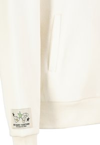 White sweatshirt featuring a ribbed hem, side pocket, and a label with a graphic design that includes text and cartoon elements.