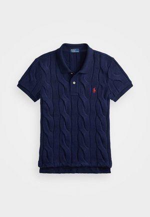 Polo bleu marine en tissu tricoté avec un motif en cable, patte de boutonnage à deux boutons et un petit emblème rouge sur la poitrine gauche.