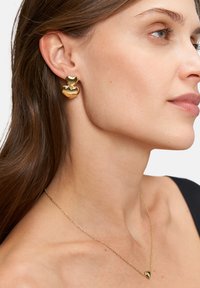 Gouden hartvormige oorbellen met twee lagen, een gepolijste afwerking, en een bijpassende gouden ketting met een klein hartje als hanger.