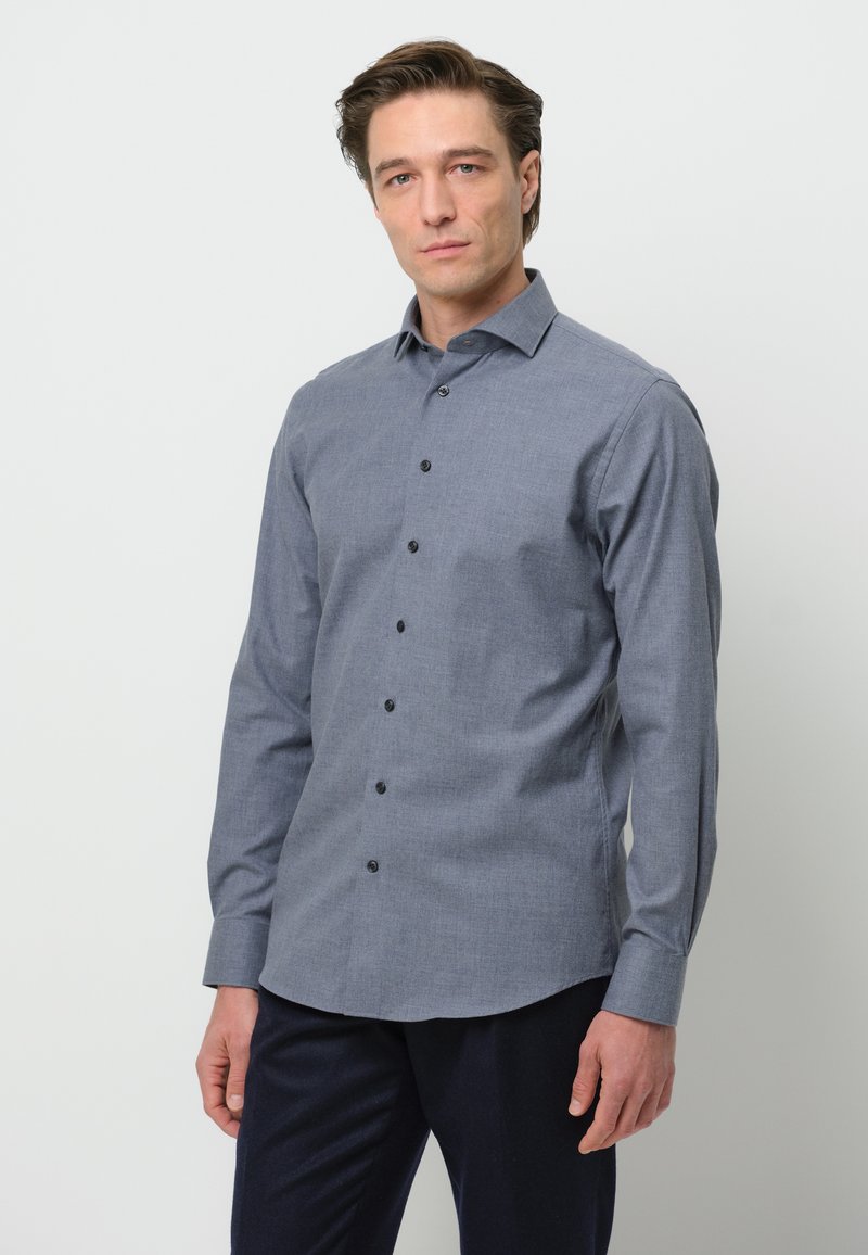 Camicia button-up in tessuto grigio scuro con una sottile texture, dotata di colletto a punta, maniche lunghe e bottoni neri lungo la parte anteriore.