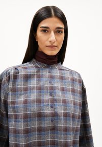 Button-up Hemd mit einem grauen Karomuster, das blaue und burgunderfarbene Akzente aufweist, aus strukturiertem Stoff und einem hohen Kragen mit puffigen Ärmeln.