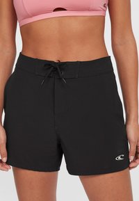Sorte svømmeshorts med flat linning, justerbar snor og en liten hvit logo nederst til venstre. Glatt, lett stoff.