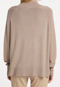Lichtbruin sweater met een geribbelde halslijn en manchetten, lange mouwen en een relaxte pasvorm. Zachte textuur met een iets langere achterkant.