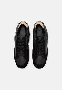 Sneaker nere con esterno in pelle liscia, dettagli in suede texture, chiusura con lacci e colletto imbottito beige. Logo stampato sulla soletta.