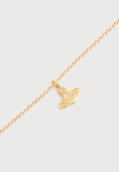 Gold chain bracelet with a small gold charm shaped like a stylized planet with rings and a cross on top.