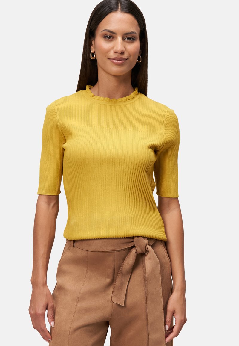 Geel geribbelde gebreide top met een gekartelde halslijn en korte mouwen, gecombineerd met bruine hoge taille broeken met een strikdetail bij de taille.