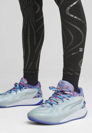 Scarpe da ginnastica blu e rosa presentano una parte superiore testurizzata con un motivo multicolore, una suola intermedia bianca e una suola esterna viola. Vengono indossati leggings neri con motivo.