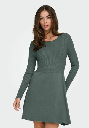 Robe à manches longues en velours côtelé de couleur vert foncé, avec un corsage ajusté et une jupe évasée, dotée d'un col rond et d'une texture douce.