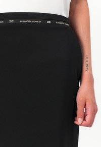 Svart skjørt laget av glattt stoff, med en merket midjebånd med "ELISABETTA FRANCHI" i hvitt. Har en tettsittende silhuett.