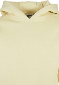 Felpa gialla chiara con cappuccio regolabile, texture morbida e polsini e orlo a coste. L'etichetta nell'area interna del collo riporta informazioni sul brand.
