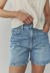 Denimshorts i ljusblått med en klassisk passform, utrustade med knäppning fram, bälteshällor och sidofickor, tillverkade av strukturerad tyg.