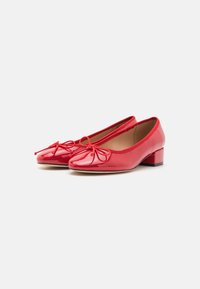 Red patent leather ballet flats with a small block heel, featuring a bow detail on the toe and a smooth, shiny texture.