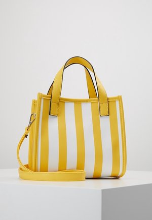 Mała torebka z żółtymi i białymi pionowymi paskami, podwójnymi górnymi uchwytami oraz odpinanym paskiem na ramię, umieszczona na białej powierzchni.