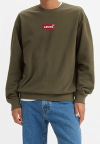 Felpa girocollo verde oliva realizzata in tessuto misto cotone, caratterizzata da un patch ricamato rosso con il logo Levi's sul davanti. Fit casual con polsini a coste.