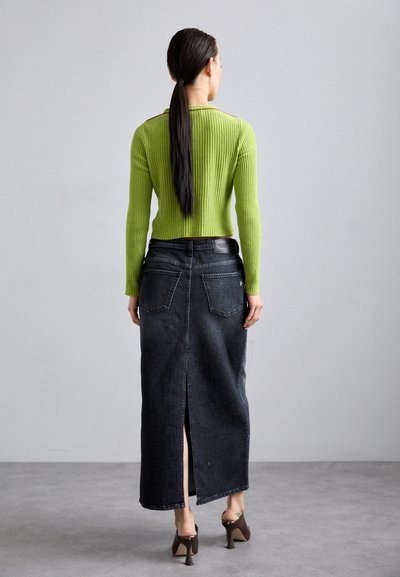 Maglietta verde a maniche lunghe con coste abbinata a una gonna maxi in denim scuro a vita alta con uno spacco posteriore e due tasche sul retro.