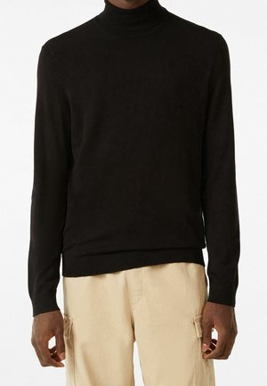 Suéter negro de cuello alto con mangas largas, hecho de una tela suave; con cuello y dobladillo acanalados; combinado con pantalones cargo en un tono beige claro.