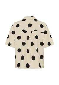 Chemise beige à manches courtes avec de gros pois noirs, dotée d'un col et d'un empiècement arrière avec un pli central.