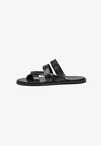 Sandalias negras con tres correas texturizadas y un diseño de punta abierta. El material tiene un patrón de piel de cocodrilo, y la suela es plana y sencilla.