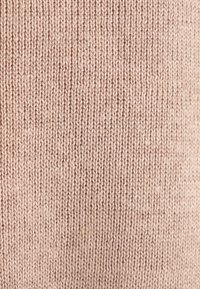 Strickstoff in sanftem Rosaton, der eine glatte Textur aufweist, die durch gleichmäßig verteilte Stiche erzeugt wird, und ein konsistentes Muster durchgehend zeigt.
