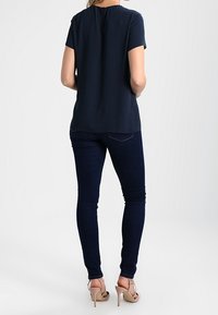 Námořnická blůza s krátkým rukávem a jemným záhybem u krku, spárovaná s tmavými skinny džíny a světlými podpatky.