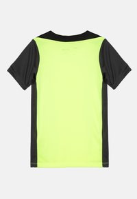 Camiseta deportiva de manga corta con un frente amarillo brillante y mangas negras. Confeccionada en una tela ligera con una textura suave y un cuello redondo.