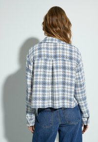 Blauwe en witte geblokte flanellen shirt met een kraag, met lange mouwen en een relaxte pasvorm. De stof heeft een gestructureerde uitstraling.