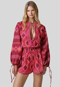 Romper colorato e con fantasia in tonalità di rosa, caratterizzato da una vestibilità ampia, maniche lunghe e una vita regolabile con un profondo scollo.
