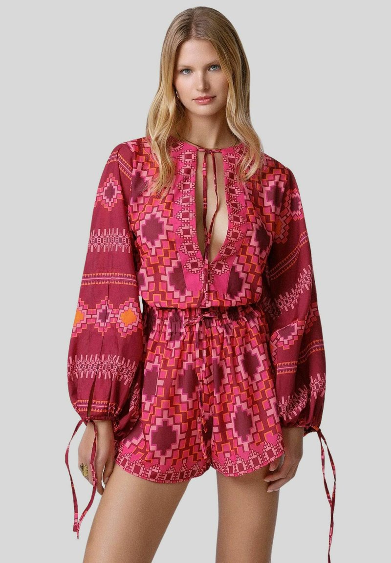 Romper colorato e con fantasia in tonalità di rosa, caratterizzato da una vestibilità ampia, maniche lunghe e una vita regolabile con un profondo scollo.