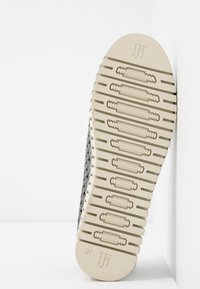 Sole di sneaker in bianco e nero con un motivo di grip testurizzato, intersuola beige e taglia 37 incisa sul fondo.