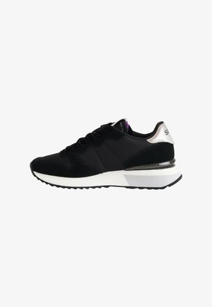 Baskets de sport noir et blanc avec une semelle rembourrée, un devant à lacets et un accent de talon argent métallisé.