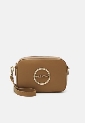 Borsa a tracolla in pelle marrone con hardware circolare dorato e logo impresso. Presenta una chiusura a zip e una tracolla removibile. Forma rettangolare compatta.