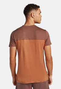 T-shirt a maniche corte con un design bicolore, dotato di una parte superiore marrone scuro e una parte inferiore marrone chiaro, realizzato in tessuto testurizzato.