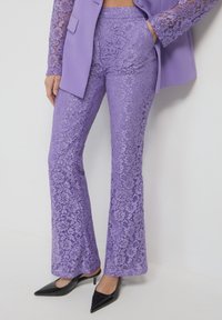Pantaloni a zampa d'elefante viola in pizzo con un motivo testurizzato, abbinati a un blazer fitted coordinato con maniche in pizzo e tasche.
