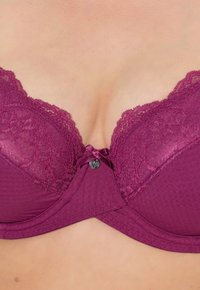 Mauve push-up rintuli, jossa on pitsiyksityiskohtia, pieni bow keskellä, napin korostus ja sileä kangas.