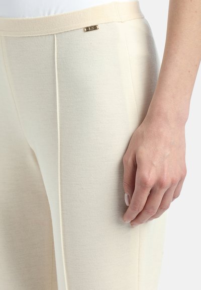 Beige hlače od teksturiranog materijala, s glatkim pojasom i malim zlatnim logotipom sprijeda. Slim fit dizajn.