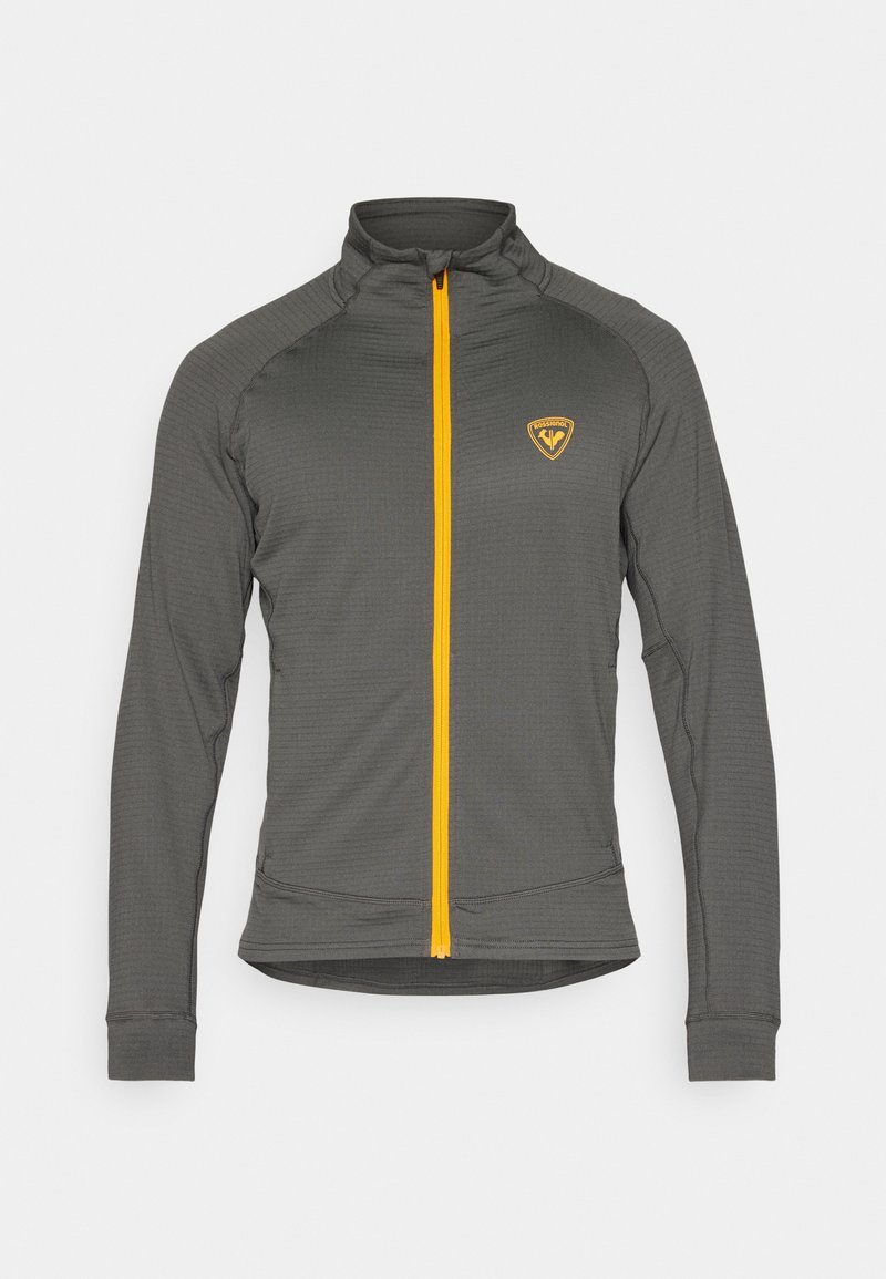 Szara, długopisowana kurtka zapinana na zamek z wysokim kołnierzem, jasnopomarańczowy zamek błyskawiczny i małe pomarańczowe logo na lewej piersi.