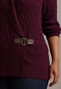Vivid burgundy cable-knit cardigan with a wrap design, featuring a brown leather belt and gold-tone buckle. Ribbed cuffs and hem.