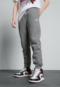 Pilkos džinsinės treninginės kelnės su siaurėjančiu dizainu ir baltu Jumpman logotipo ženklu. Suderinta su juodais, baltais ir bordo sportiniais batais.